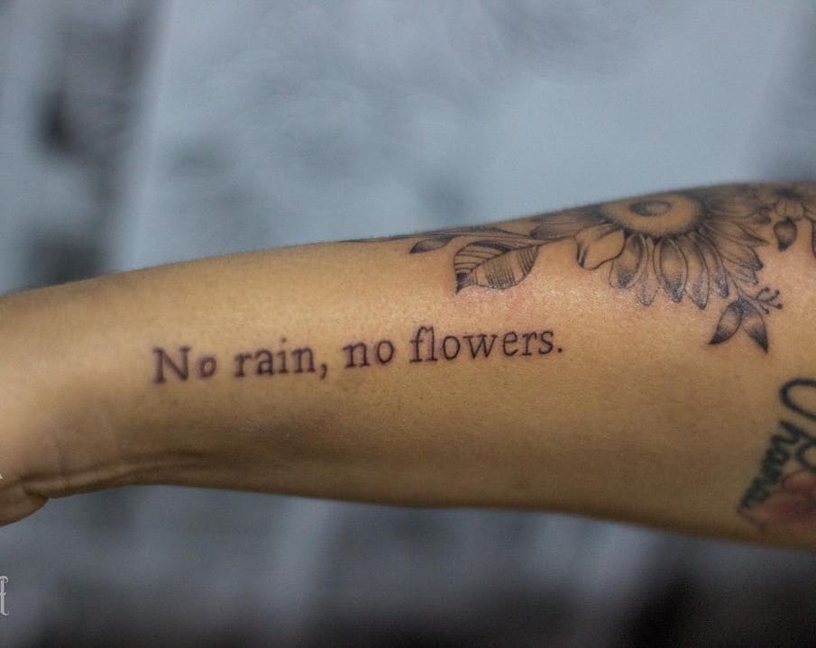 "no rain no flowers" tattoo along the forearm