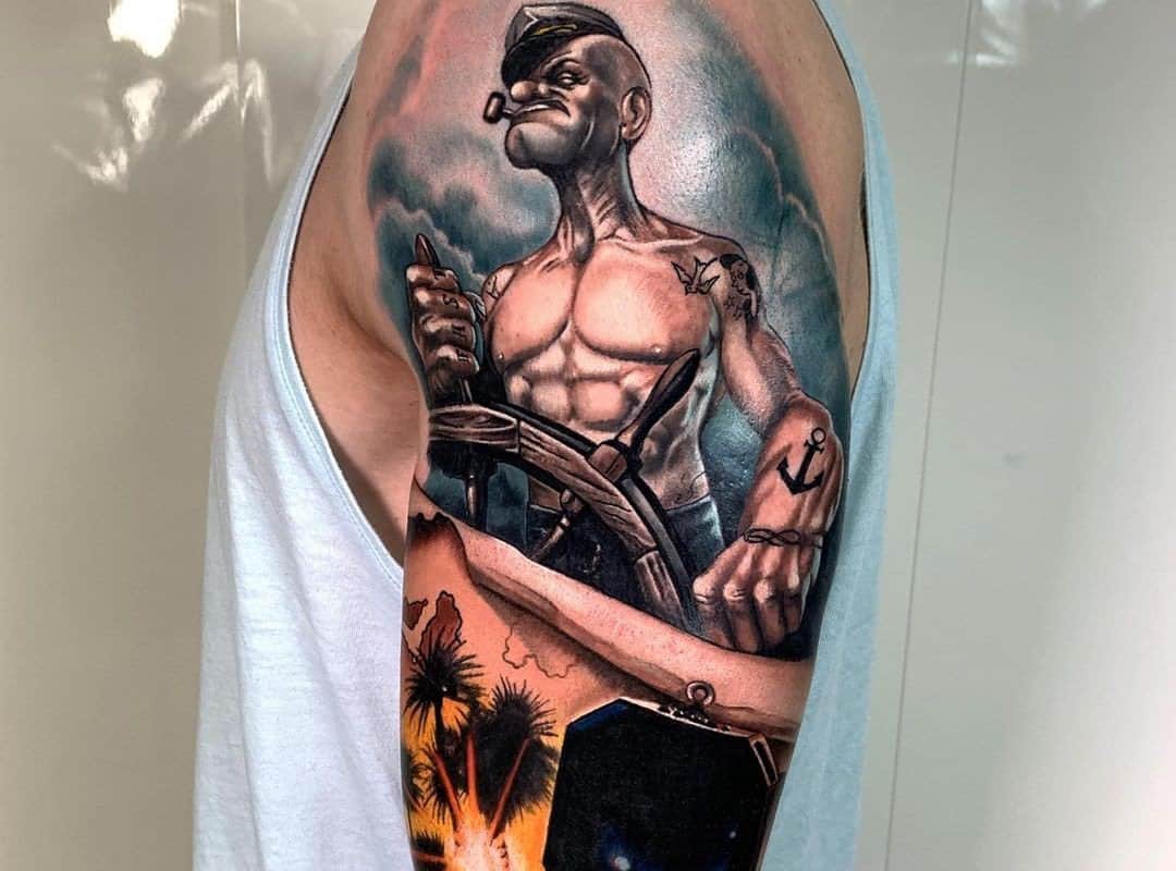 colored tattoo of a Popeye sailor tattooed on his shoulder