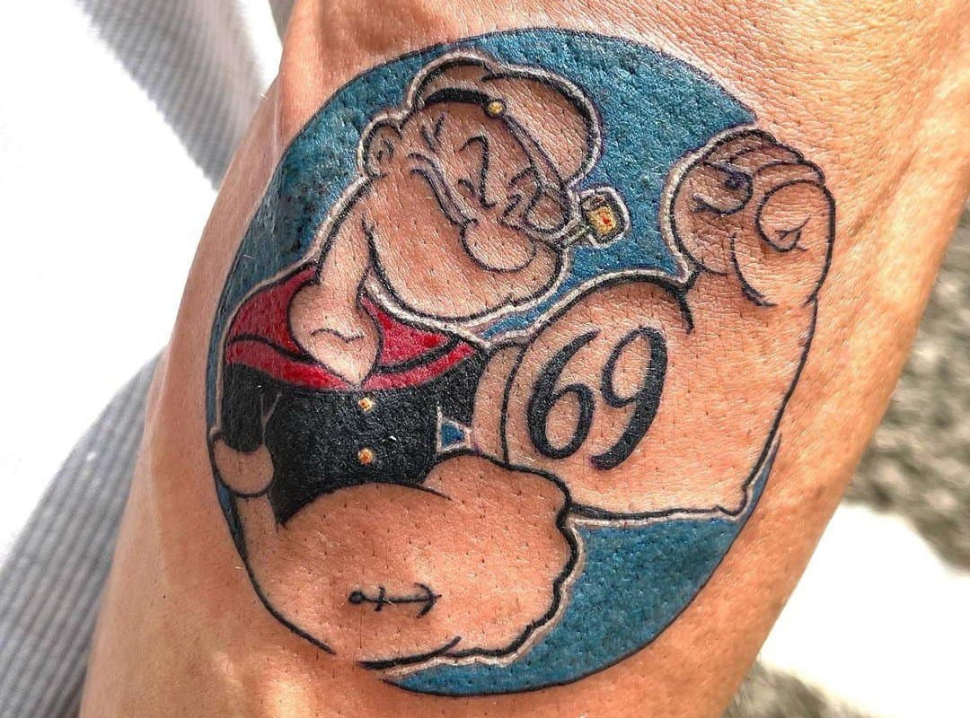 A tattoo of a Popeye sailor showing his biceps
