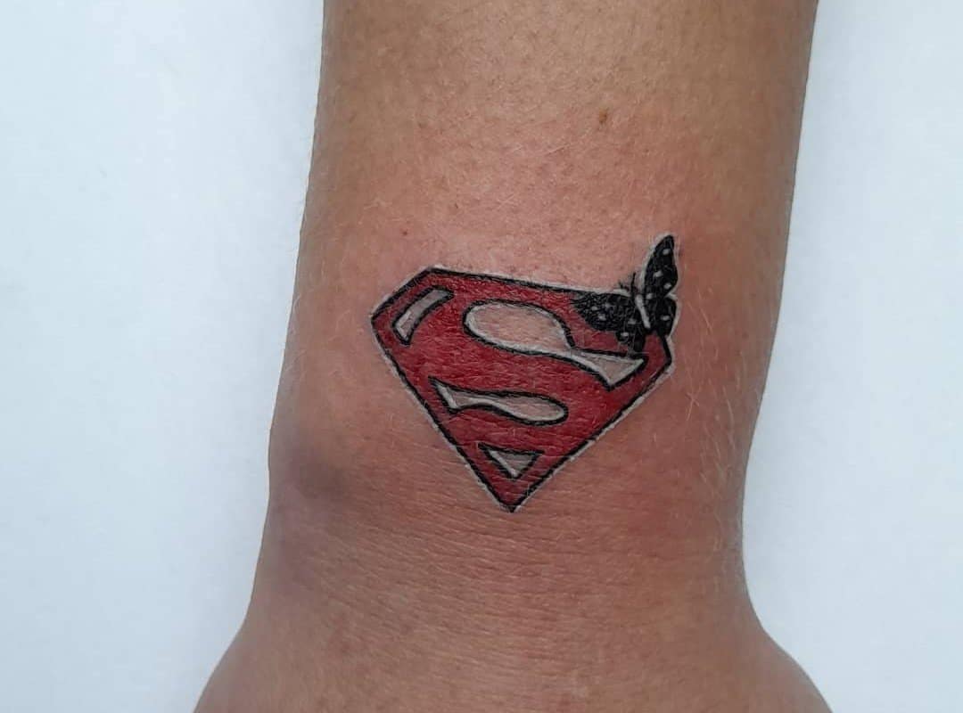 Superman emblem tattoo and a butterfly on it