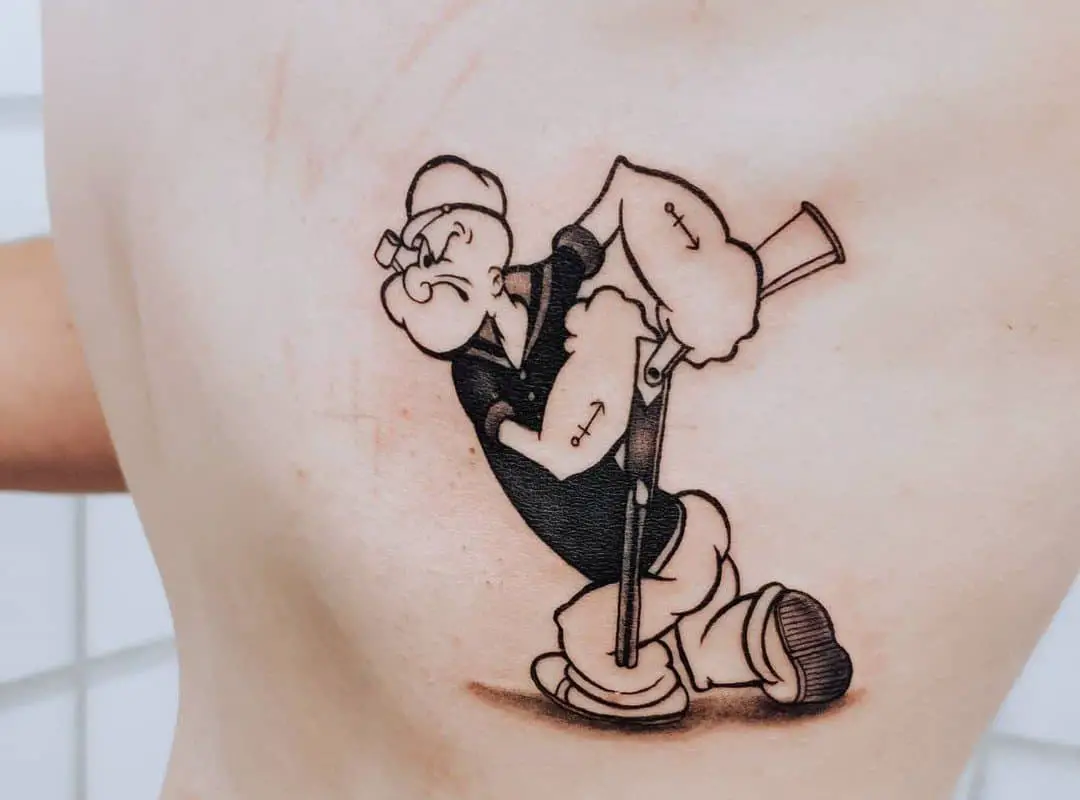 A black and white tattoo of a Popeye sailor tattooed on the back