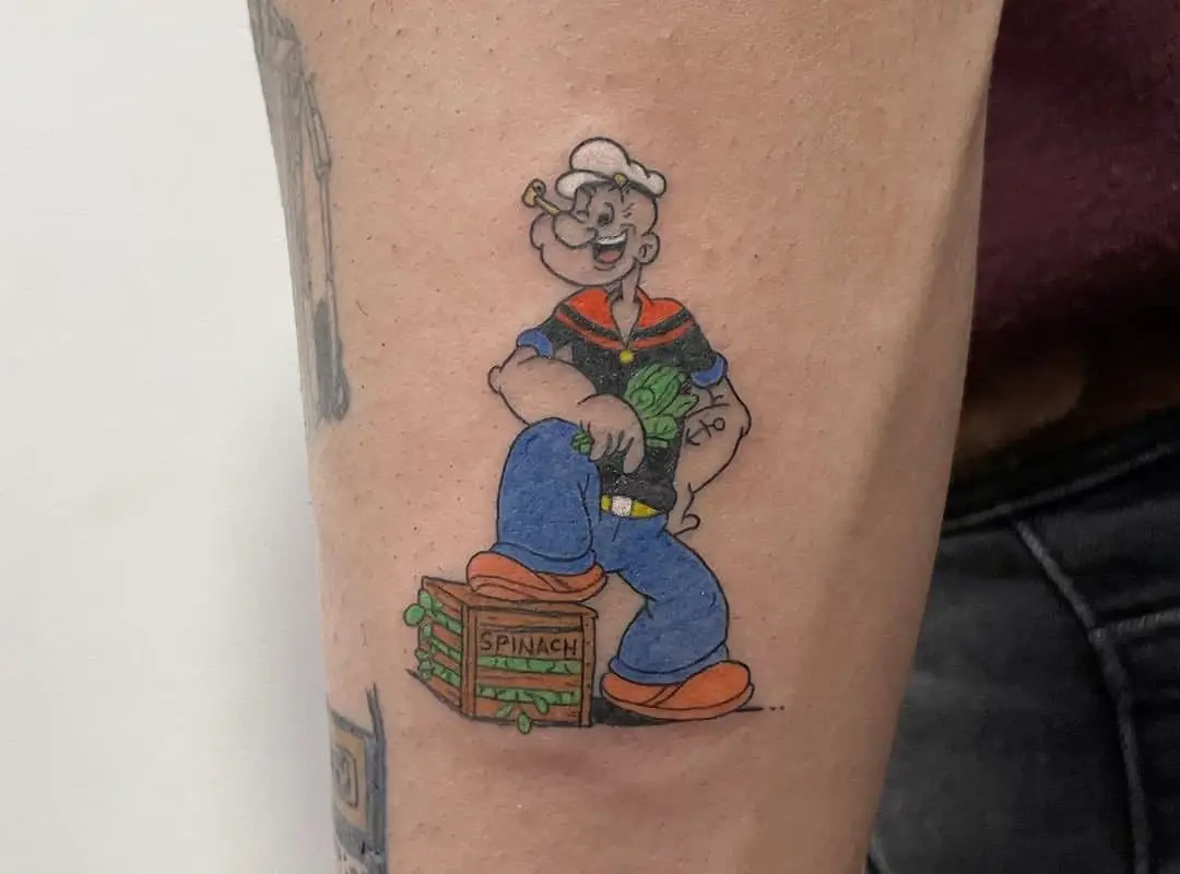 A tattoo of a Popeye sailor standing on a box of spinach