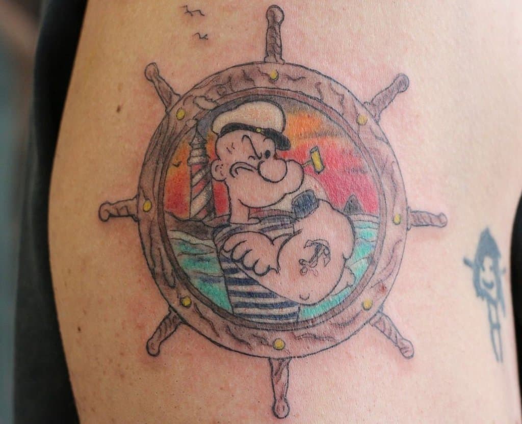 Sailor Popeye tattoo with the sea and the helm in the background