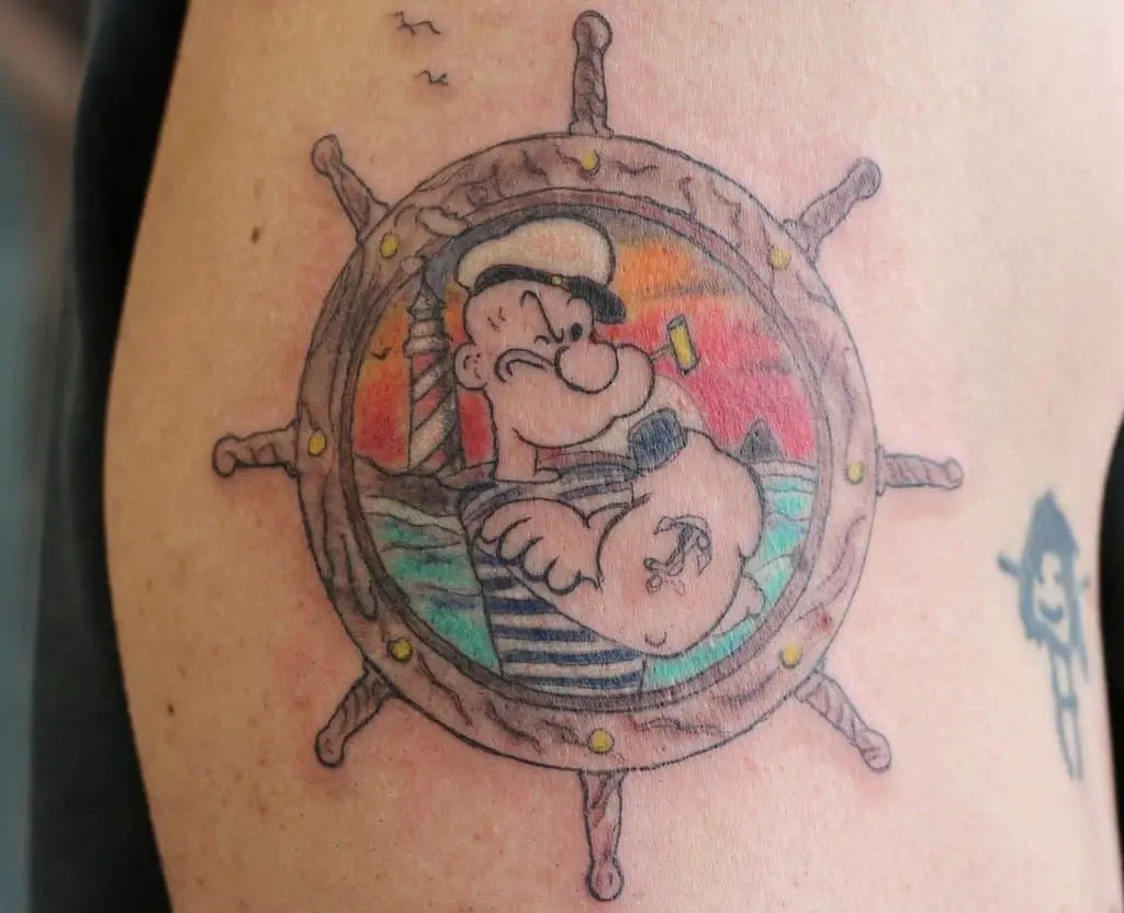 Sailor Popeye tattoo with the sea and the helm in the background