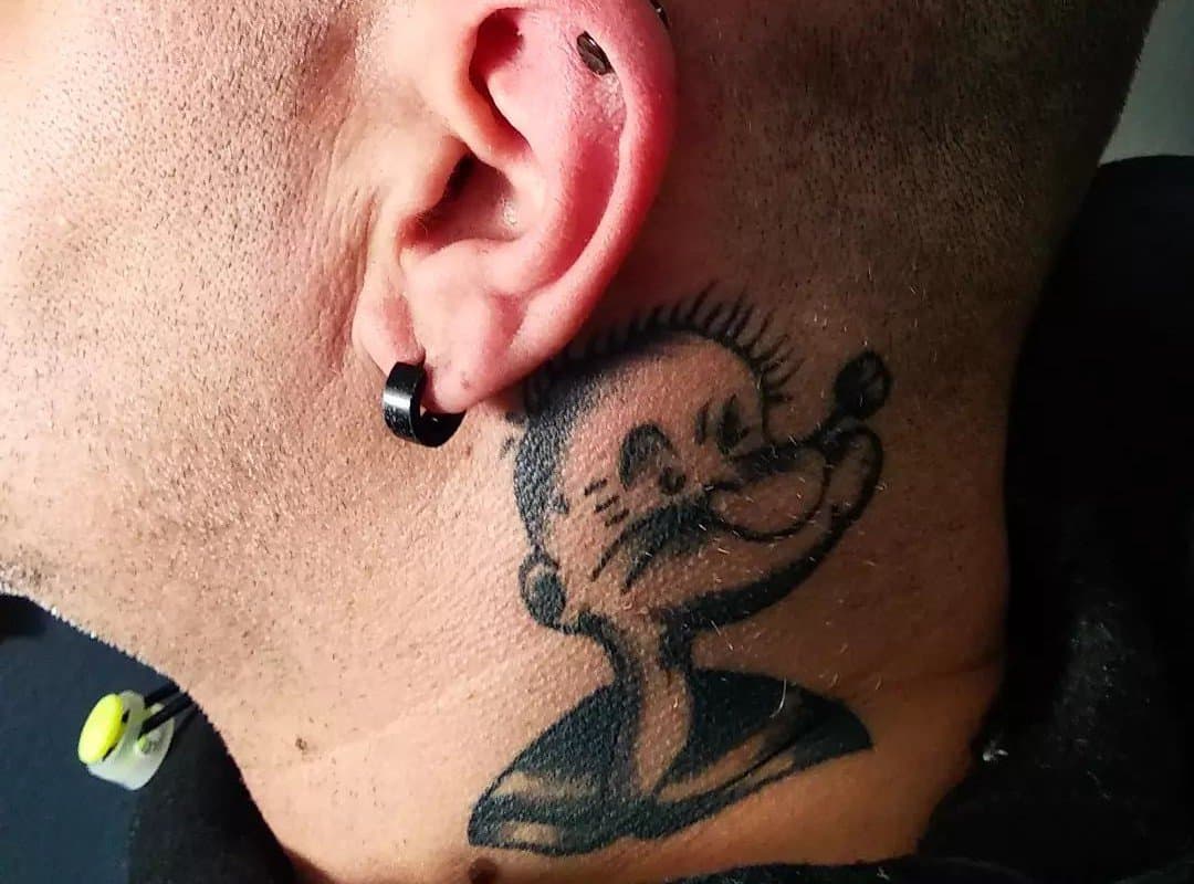 a black and white tattoo of a Popeye sailor behind the ear