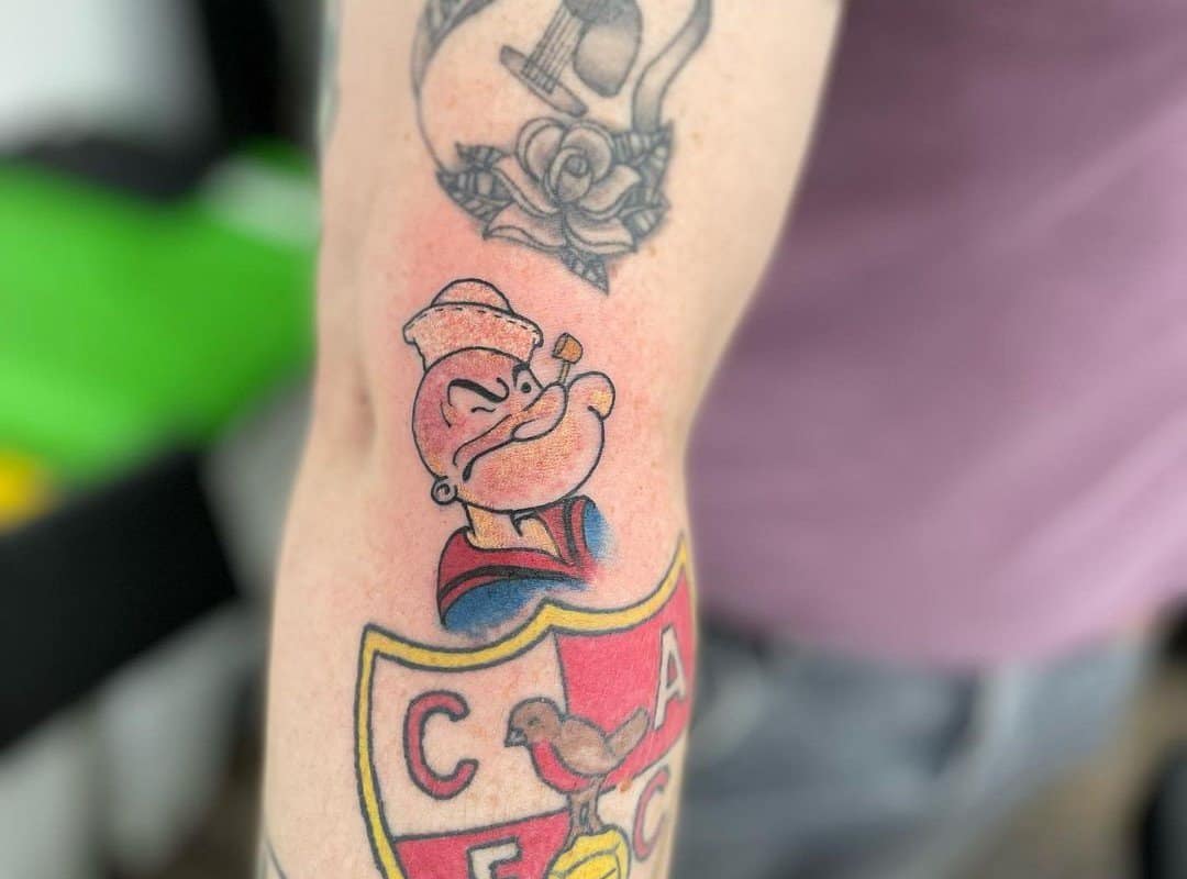 A tattoo of a Popeye sailor with a disgruntled face