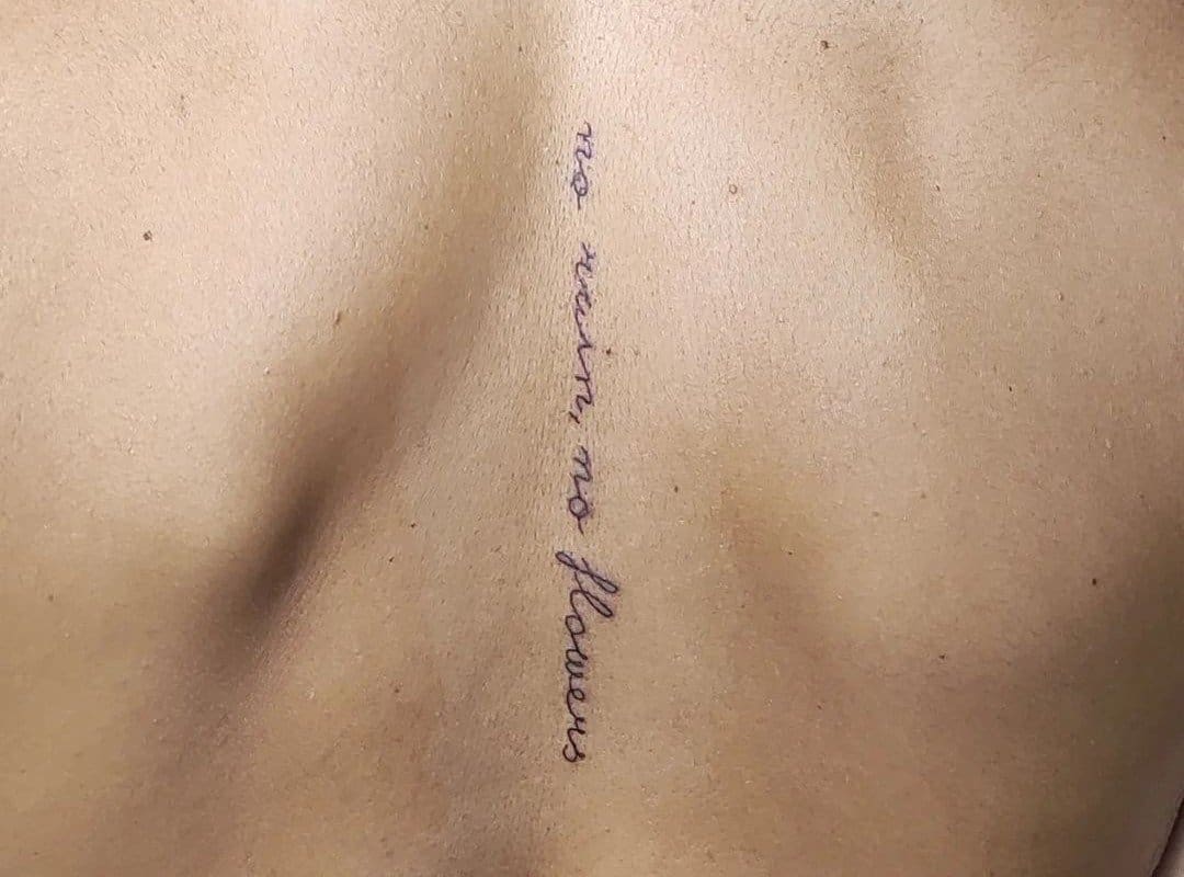 "no rain no flower" tattoo between the shoulder blades