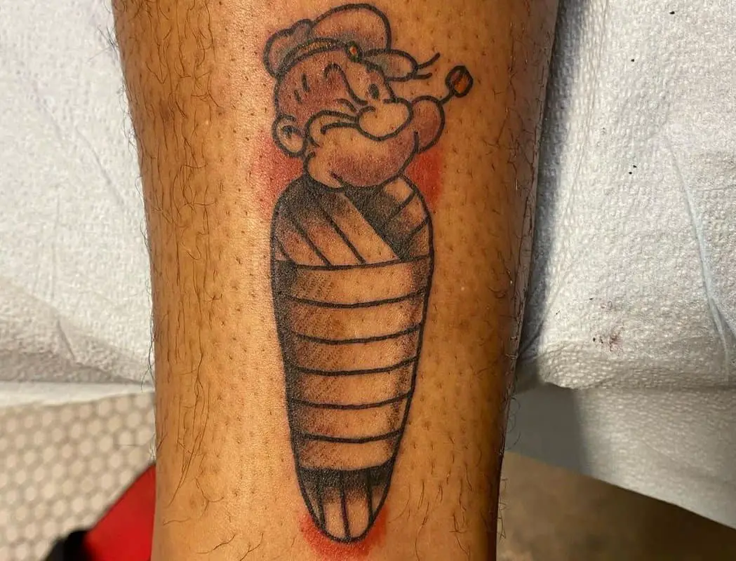 a tattoo of a papaya sailor wrapped up like a mummy