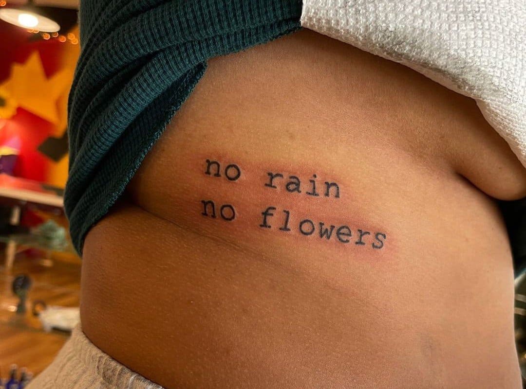 motivational tattoo on the side "no rain no flowers" 