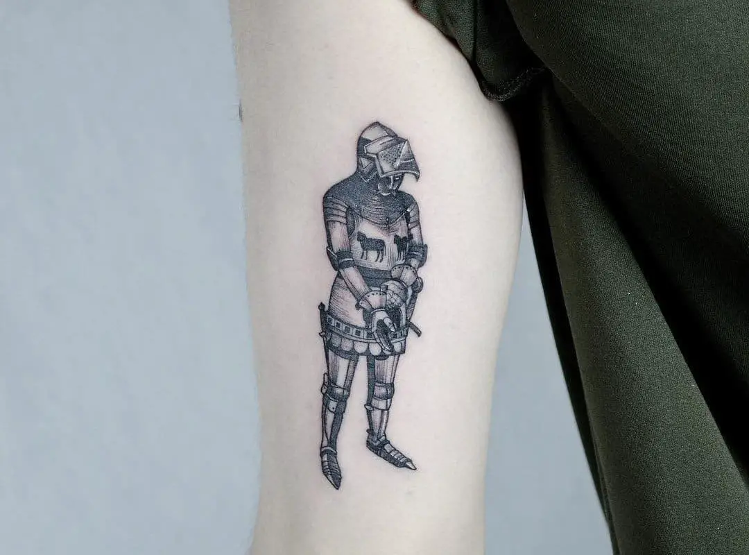 a black and white tattoo of a knight on his arm