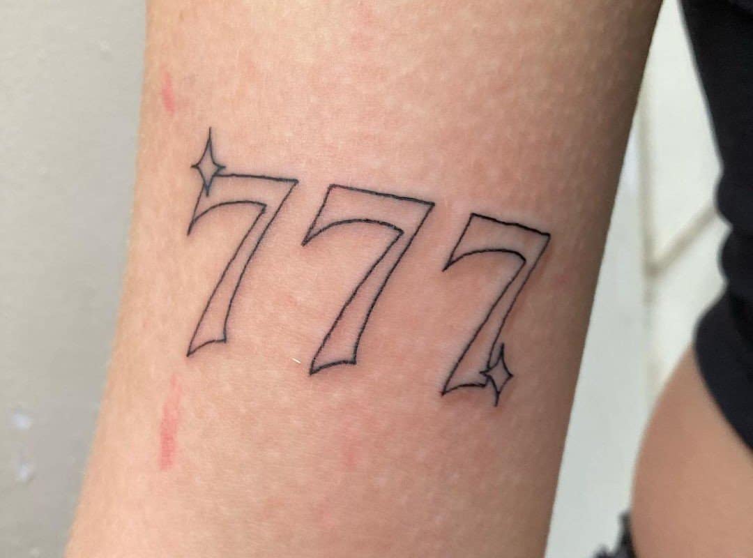 Tattoo of three sevens with asterisks at the beginning and end