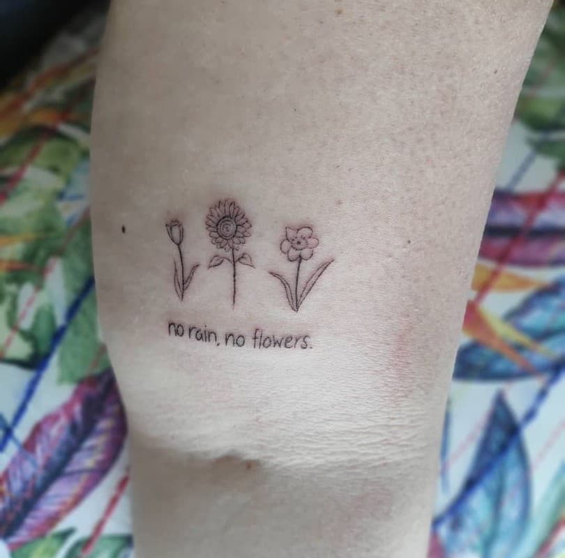 tattoo of three flowers and an inscription