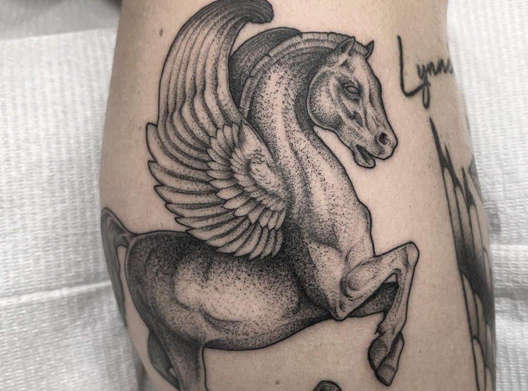 a black and white tattoo of a pegasus on shin