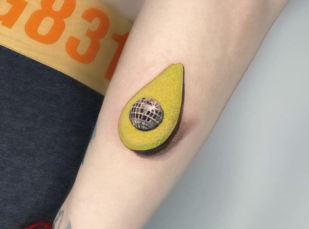 Avocado tattoo with a disco ball instead of a bone