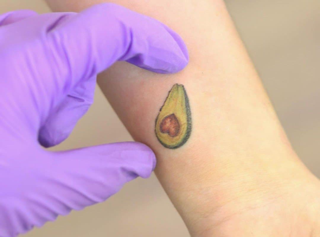 Purple gloved hand shows avocado tattoo