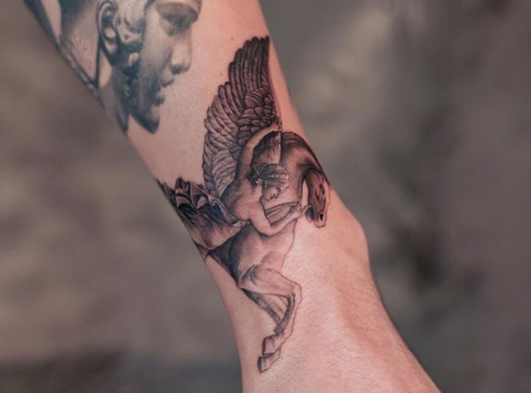 A tattoo of a pegasus and a rider next to it