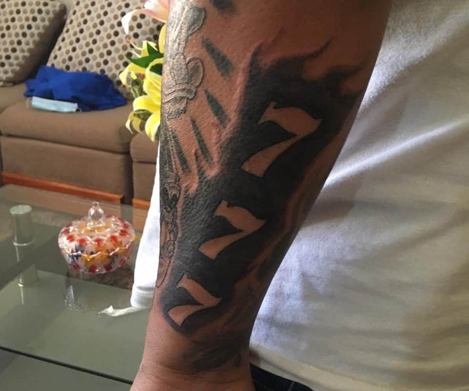 Tattoo of three sevens on the forearm above each other