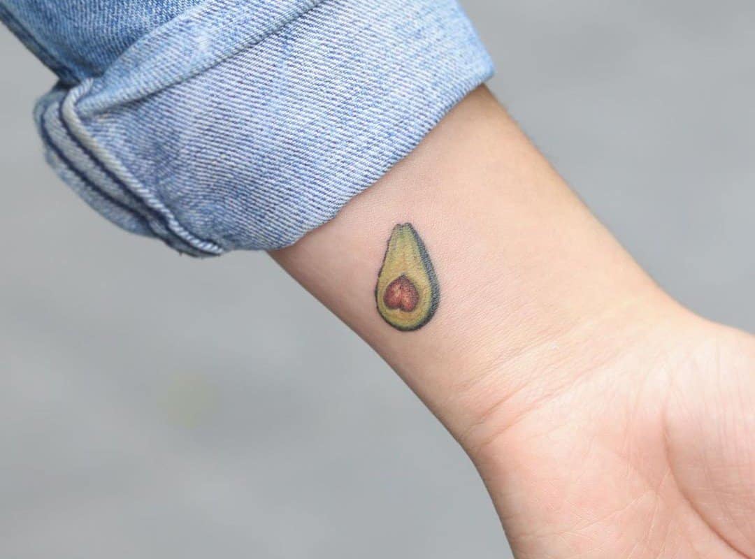 a small avocado tattoo on the back of the wrist
